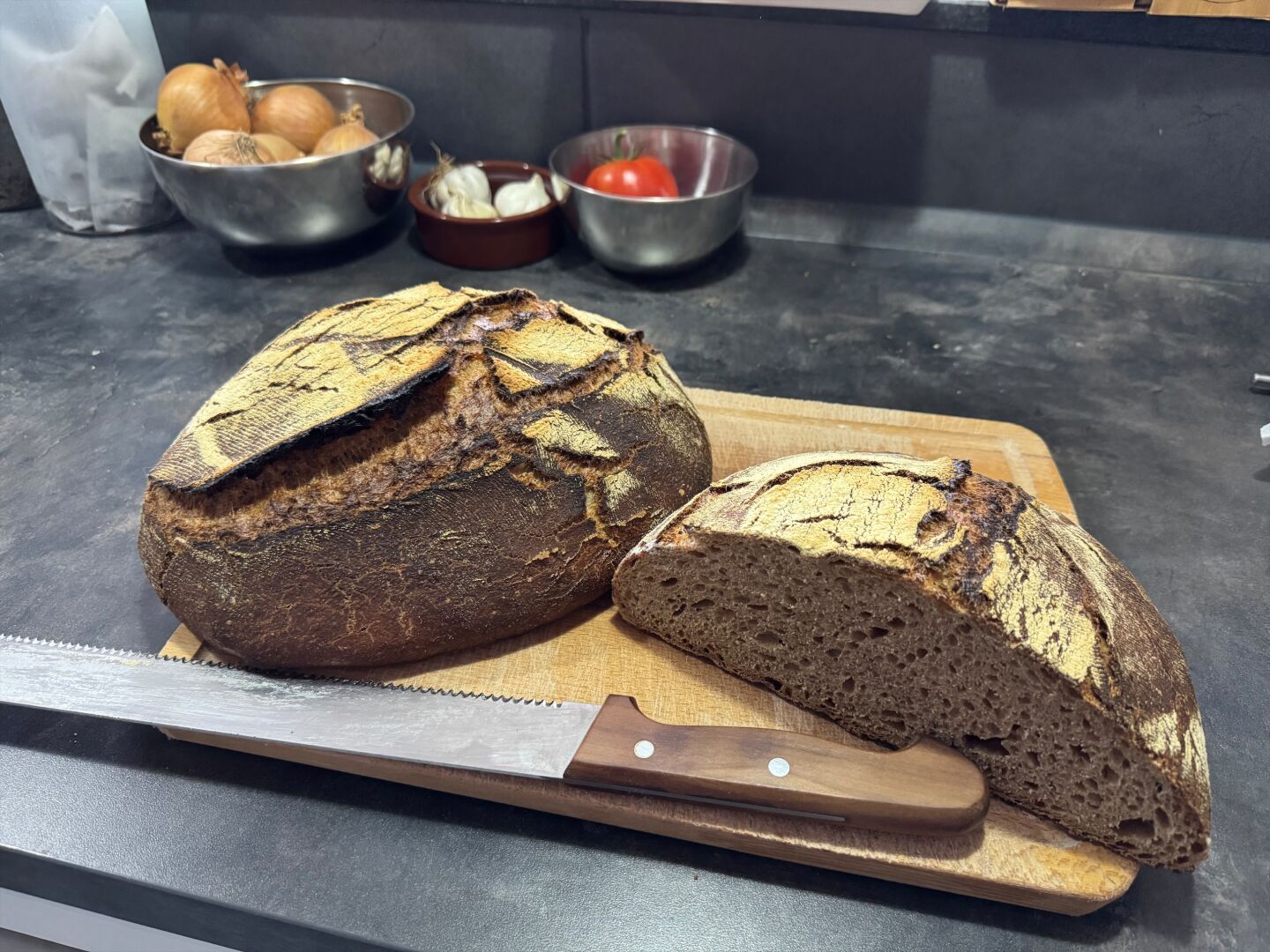 One and a half loaf of bread with a bread knife on a wooden tablet.